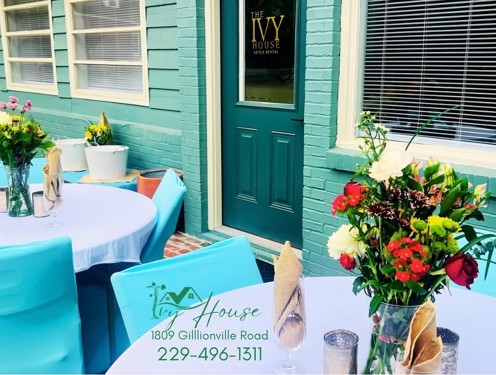 Teal front entry of The Ivy House with flowers and a welcome table